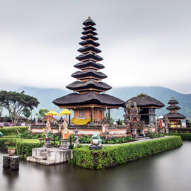 Famous Bedugul temple surrounded by colourful sun umbrellas and translucent volcanic lake