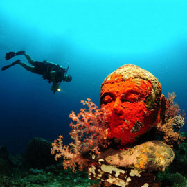 Scuba diver observing with an underwater light excitements of an underwater temple in Bali